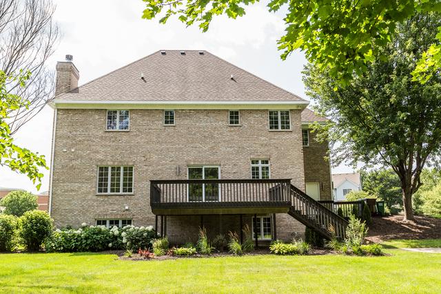 back of property with a deck and a lawn