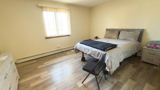 bedroom featuring a baseboard heating unit and hardwood / wood-style floors