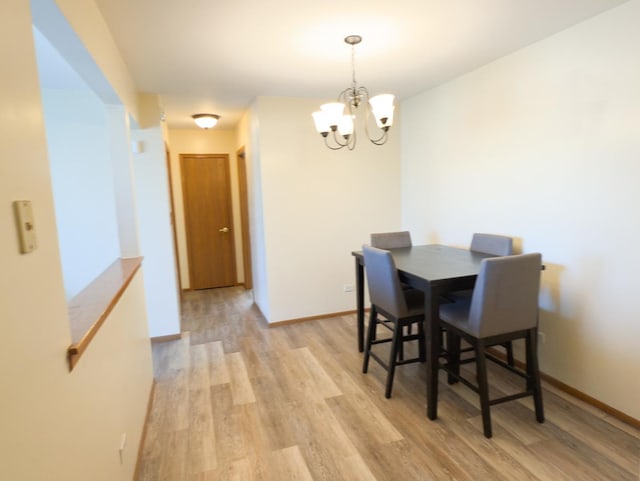 dining area with light wood-type flooring, baseboards, and a chandelier