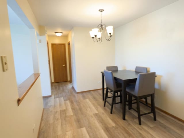 dining area with light wood-style floors, baseboards, and an inviting chandelier