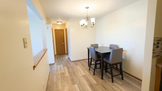 dining area featuring light hardwood / wood-style flooring and a notable chandelier