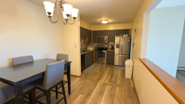 kitchen featuring sink, light hardwood / wood-style flooring, stainless steel appliances, decorative backsplash, and a chandelier