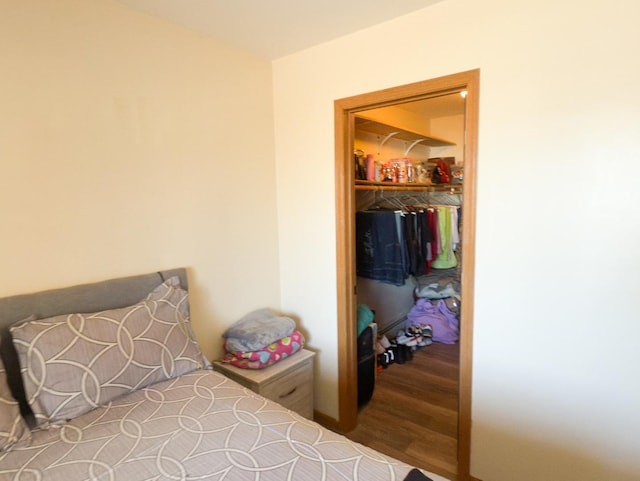 bedroom with a spacious closet and wood finished floors