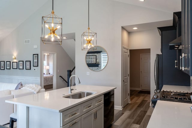 kitchen with decorative light fixtures, dishwasher, sink, dark hardwood / wood-style flooring, and a center island with sink