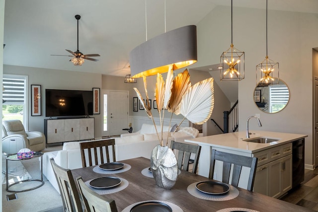 dining space featuring dark hardwood / wood-style flooring, sink, ceiling fan with notable chandelier, and vaulted ceiling