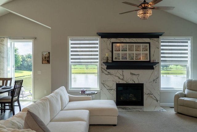 carpeted living room featuring vaulted ceiling, a healthy amount of sunlight, and a high end fireplace