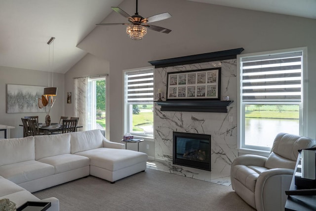 living room featuring a high end fireplace, vaulted ceiling, and ceiling fan