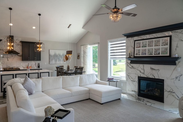 living room featuring vaulted ceiling, a premium fireplace, and ceiling fan