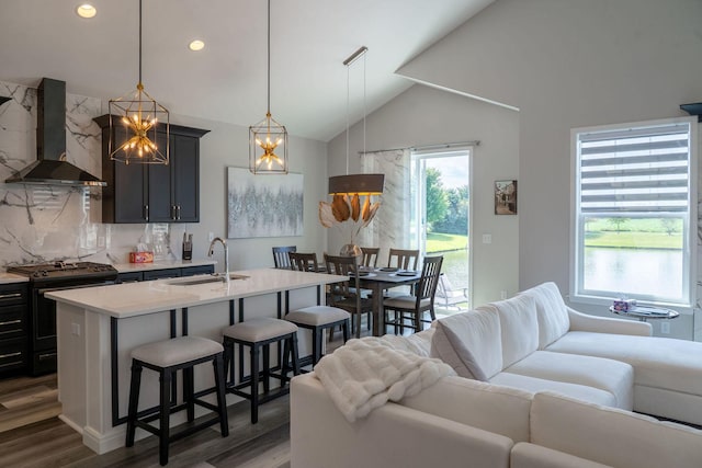 kitchen featuring pendant lighting, range with gas stovetop, sink, backsplash, and wall chimney exhaust hood