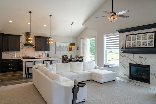 living room featuring sink, a fireplace, high vaulted ceiling, and ceiling fan