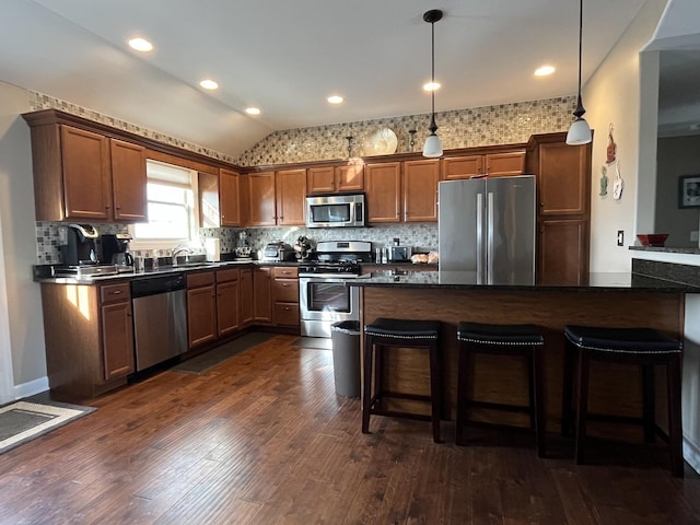 kitchen with appliances with stainless steel finishes, a breakfast bar area, sink, and hanging light fixtures