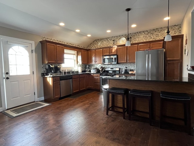 kitchen featuring lofted ceiling, sink, a breakfast bar area, hanging light fixtures, and stainless steel appliances