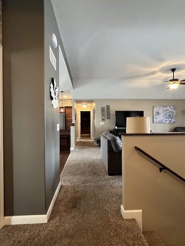 corridor with dark carpet and a textured ceiling