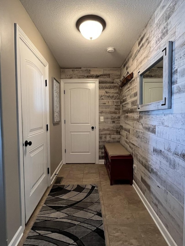 interior space with wooden walls, tile patterned floors, and a textured ceiling