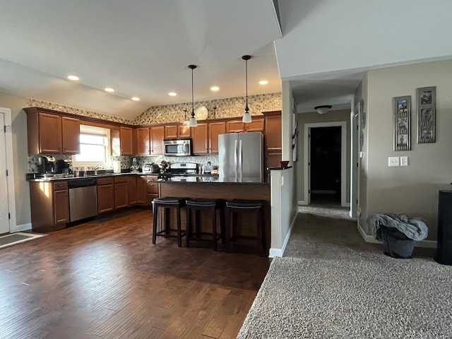 kitchen featuring pendant lighting, lofted ceiling, backsplash, a kitchen breakfast bar, and stainless steel appliances