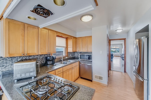 kitchen with sink, decorative backsplash, stainless steel appliances, light brown cabinets, and light wood-type flooring