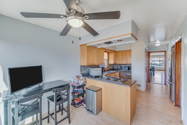 kitchen with appliances with stainless steel finishes, backsplash, light hardwood / wood-style floors, and kitchen peninsula