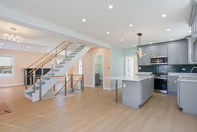 kitchen featuring pendant lighting, gray cabinets, stainless steel appliances, and a kitchen island