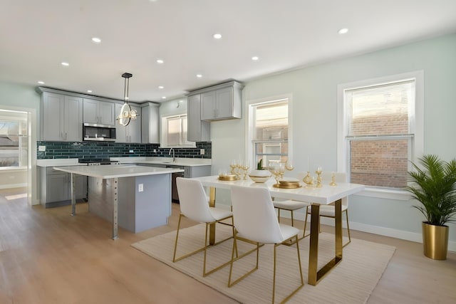 kitchen featuring gray cabinets, hanging light fixtures, a center island, and light hardwood / wood-style flooring