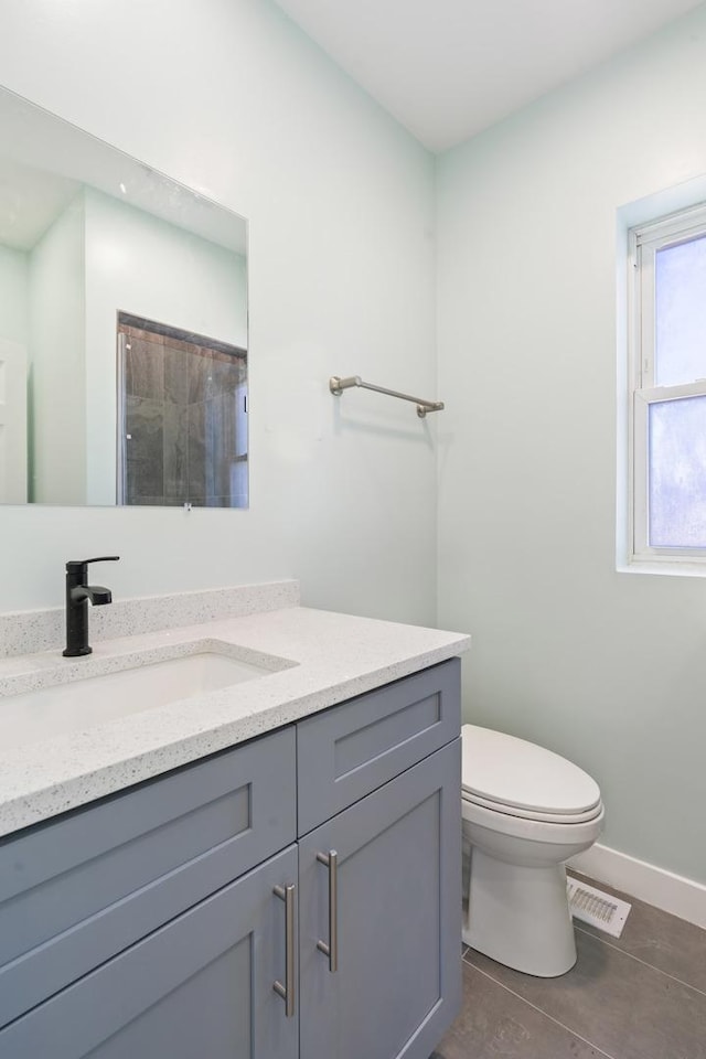 bathroom featuring vanity, a shower, tile patterned floors, and toilet