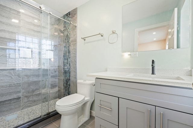 bathroom featuring walk in shower, vanity, toilet, and tile patterned flooring