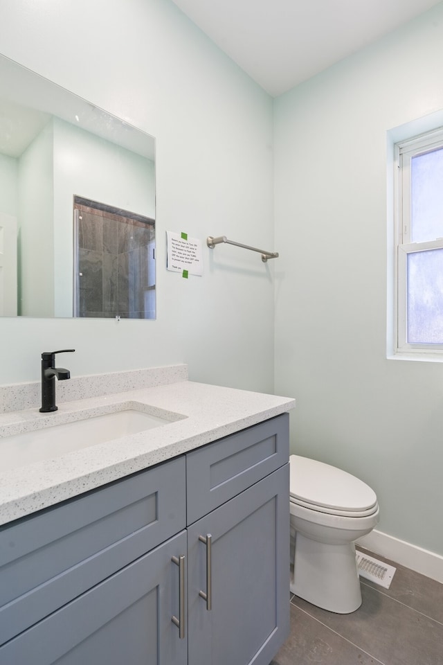 bathroom with tile patterned flooring, vanity, a shower, and toilet