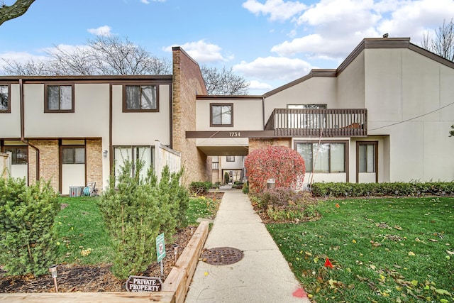 multi unit property with a balcony and a front lawn