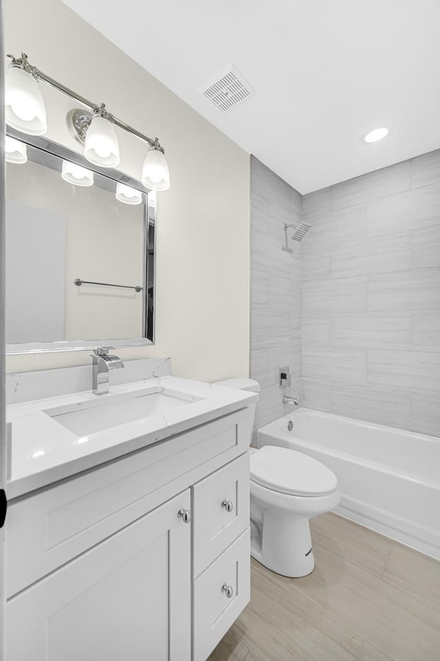 full bathroom featuring tiled shower / bath combo, vanity, and toilet