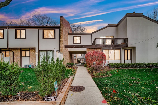 townhome / multi-family property featuring a lawn and a balcony