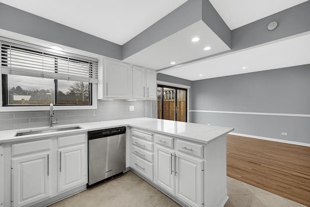 kitchen featuring white cabinetry, dishwasher, sink, backsplash, and kitchen peninsula