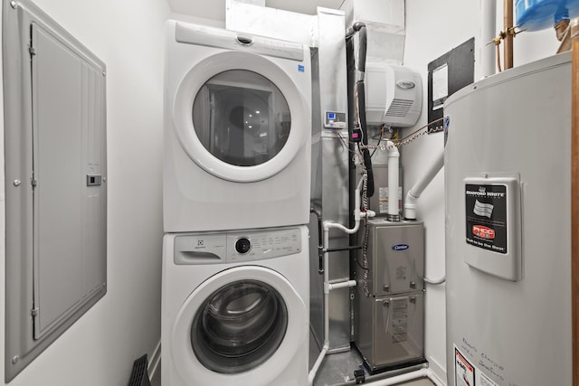 clothes washing area featuring laundry area, stacked washer / dryer, and water heater