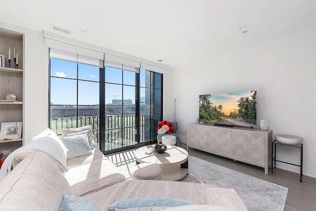 living room featuring visible vents, baseboards, wood finished floors, and expansive windows