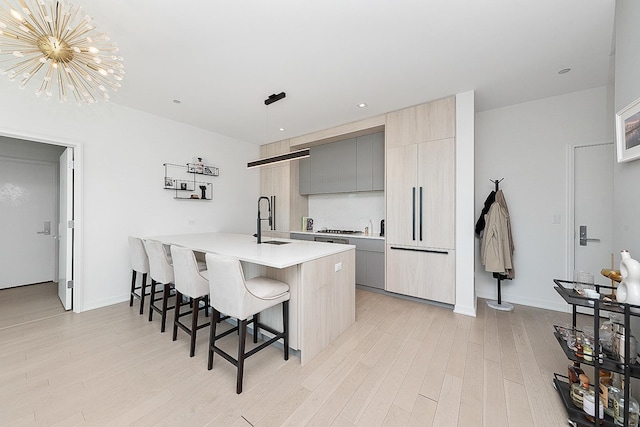 kitchen with light wood-style flooring, a sink, light countertops, a kitchen breakfast bar, and modern cabinets