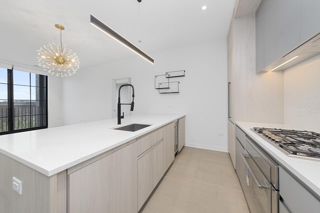 kitchen featuring a peninsula, an inviting chandelier, stainless steel gas stovetop, modern cabinets, and a sink