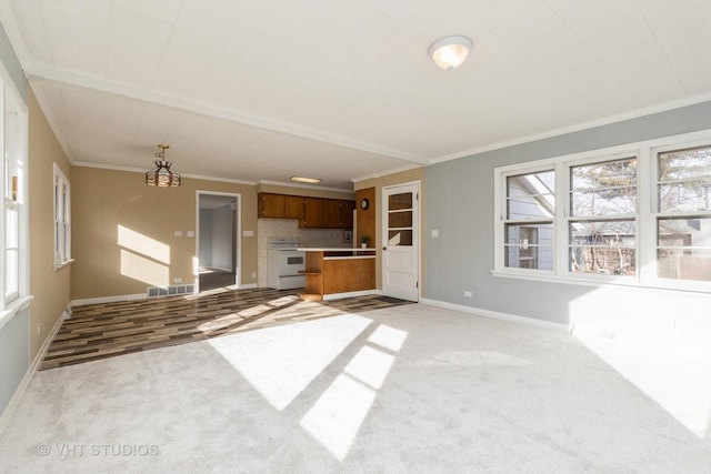 unfurnished living room with ornamental molding, light carpet, and a wealth of natural light