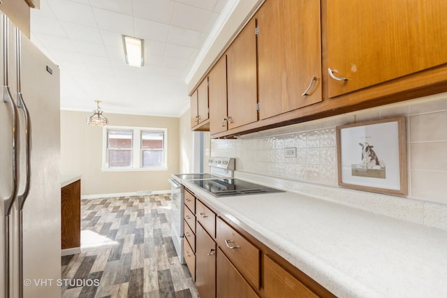 kitchen with crown molding, hanging light fixtures, light hardwood / wood-style flooring, white appliances, and decorative backsplash