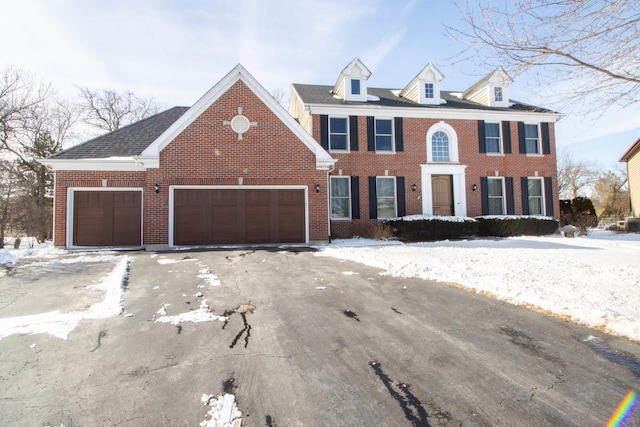 colonial-style house with driveway, brick siding, and an attached garage