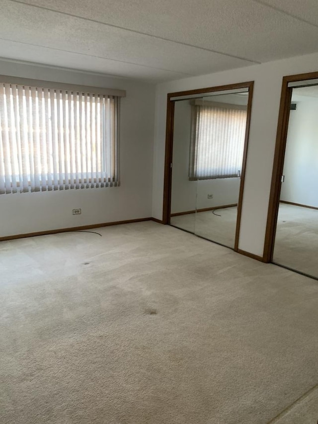 spare room featuring light colored carpet and a textured ceiling