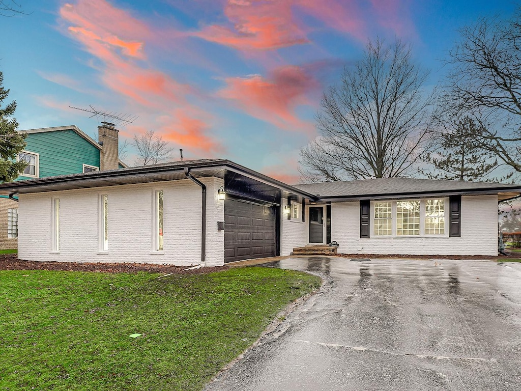 single story home featuring a garage and a lawn