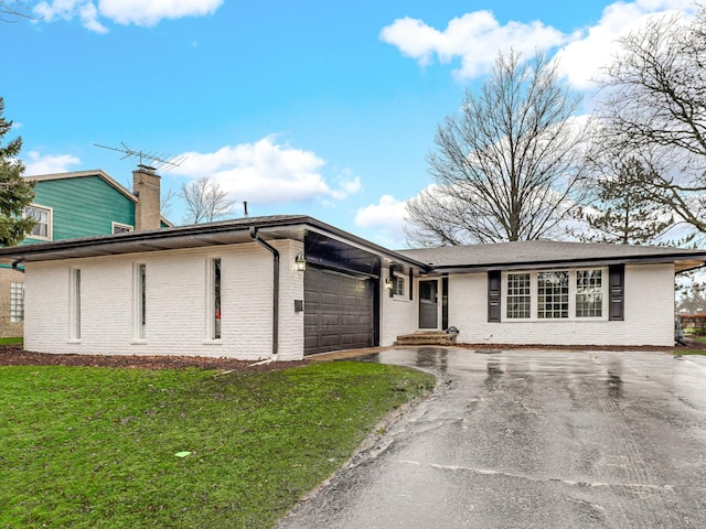 ranch-style house featuring a garage and a front lawn