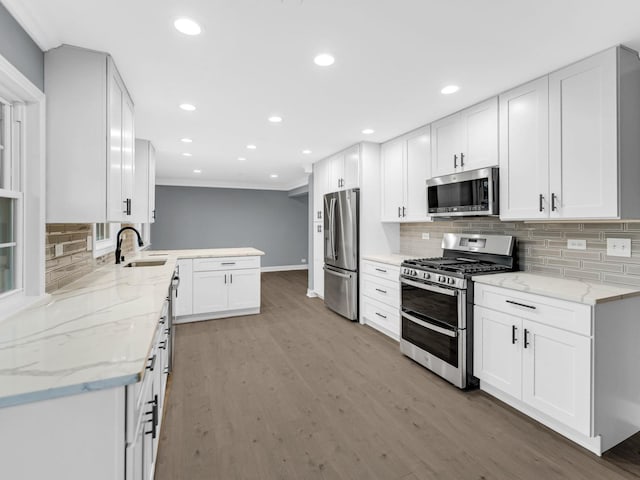 kitchen with sink, white cabinets, light stone counters, stainless steel appliances, and light wood-type flooring