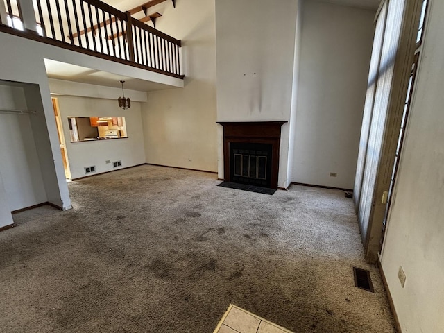 unfurnished living room with a high ceiling and carpet floors