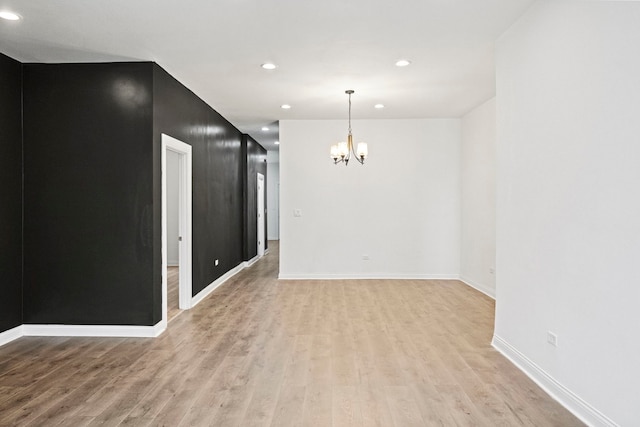 unfurnished room featuring a chandelier and light hardwood / wood-style flooring