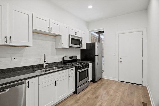 kitchen with appliances with stainless steel finishes, sink, dark stone counters, and white cabinets