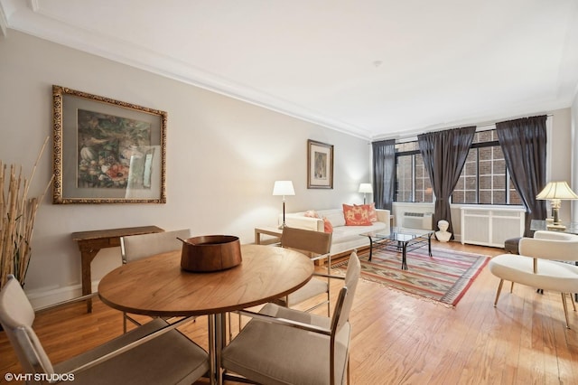 dining area featuring hardwood / wood-style flooring, crown molding, and radiator