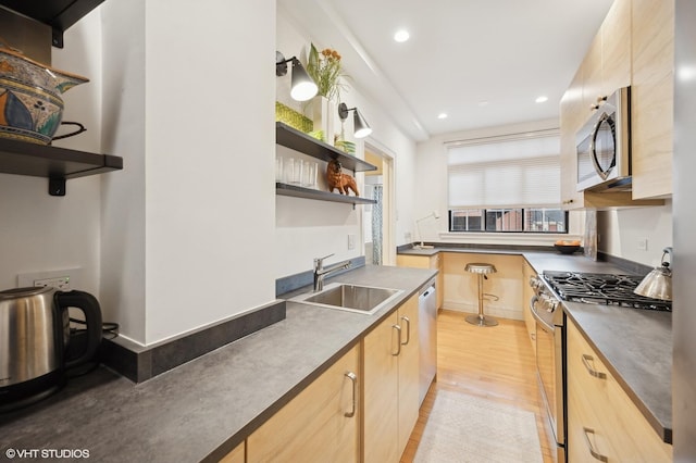 kitchen with stainless steel appliances, sink, light brown cabinets, and light hardwood / wood-style flooring