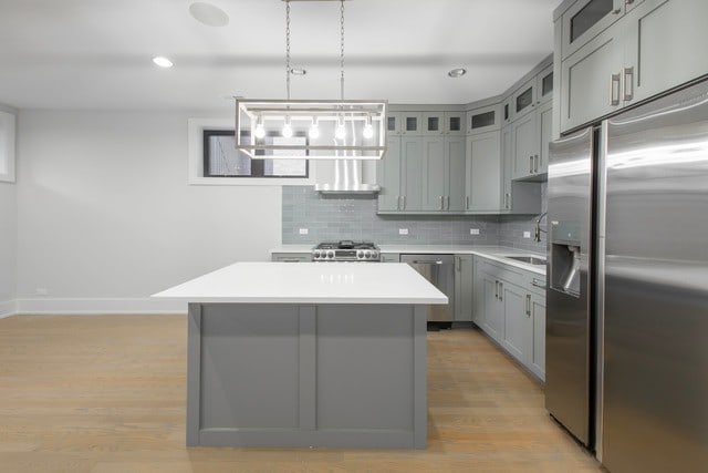 kitchen featuring backsplash, a kitchen island, hanging light fixtures, and appliances with stainless steel finishes