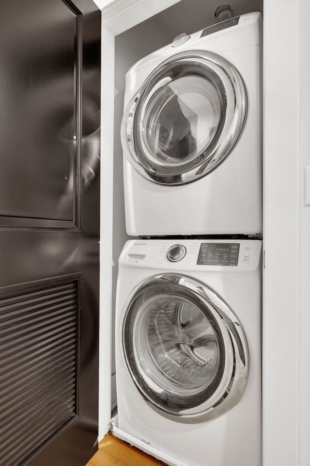 laundry area with stacked washer and dryer and light hardwood / wood-style floors