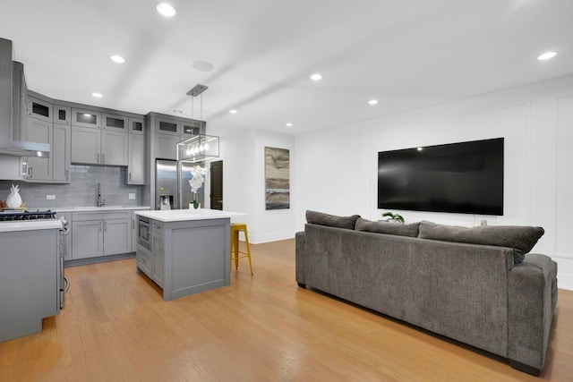 kitchen featuring sink, a center island, tasteful backsplash, decorative light fixtures, and light wood-type flooring