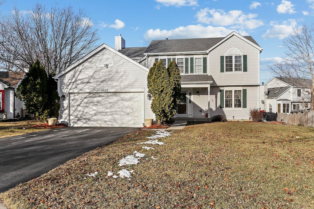 view of property featuring a garage and a front lawn